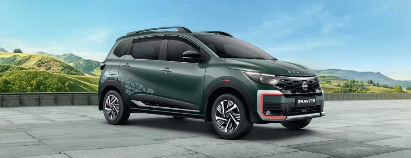 A dark green Nissan Gravite SUV with red accents and roof rails, parked in a studio with a concrete floor.